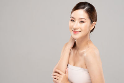 Portrait of a smiling young woman against gray background