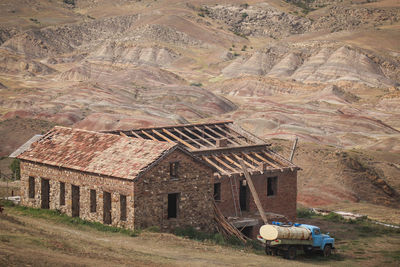 Scenic view of field by houses against mountain