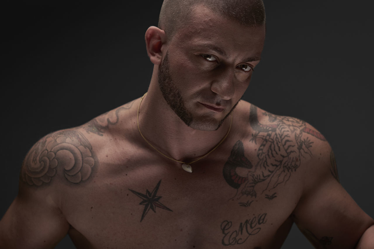 shirtless, tattoo, studio shot, black background, front view, one person, real people, muscular build, portrait, young adult, close-up