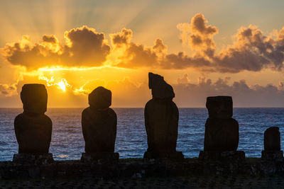 Silhouette ahu tahai statues at easter island against sky during sunset