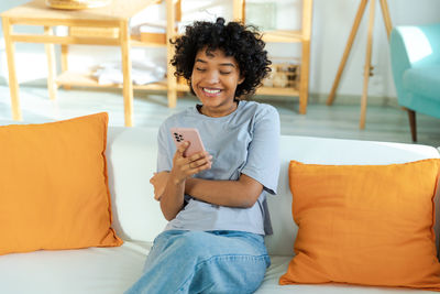 Young woman using mobile phone while lying on bed at home