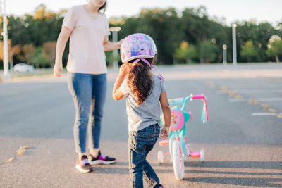 Mother and daughter standing by bicycle on road