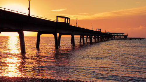 Pier over sea against sky during sunrise