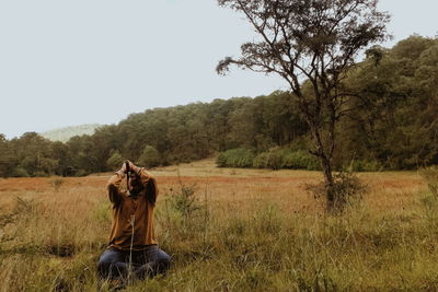 Man sitting on field against clear sky