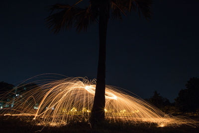 Light trails on beach against sky at night