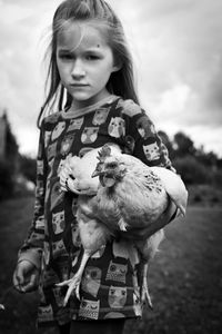 Portrait of cute girl standing on field against sky