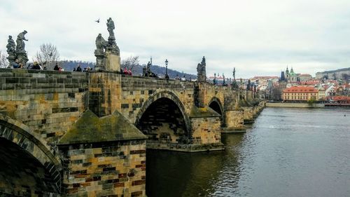 Arch bridge over river against buildings in city