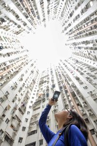 Low angle view of woman using mobile phone in city