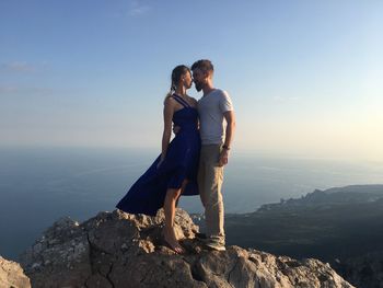 Young couple romancing on rock against sea