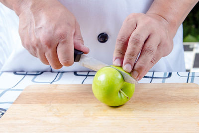 Close-up of man holding apple on table