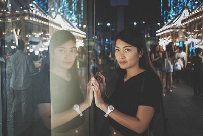 Portrait of young woman standing in city at night