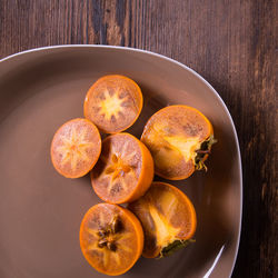 Persimmon sliced into slices in a plate on a wooden table