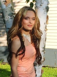 Portrait of beautiful young woman standing against wall