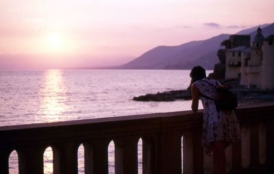 Man looking at sea against sky during sunset