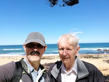 Portrait of friends at beach against clear sky