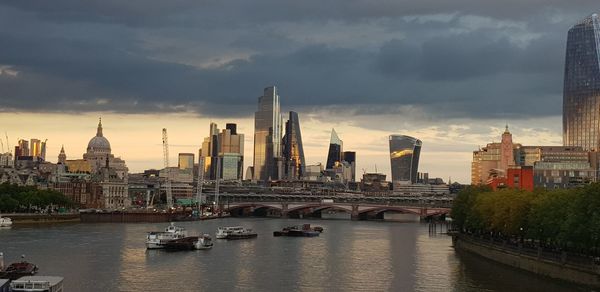 View of buildings by river against sky in city