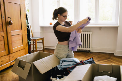 Woman folding purple hoodie during relocation of house