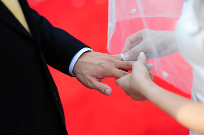 Midsection of bride putting ring in groom finger during wedding ceremony