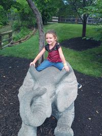 Full length of smiling girl sitting on land