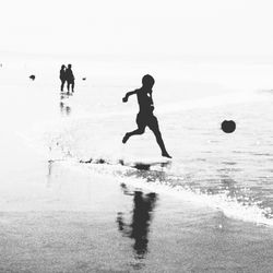 Silhouette people at beach against sky