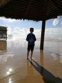 Full length portrait of young man standing on beach