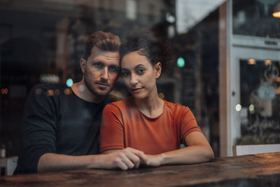 Portrait of young couple sitting on table