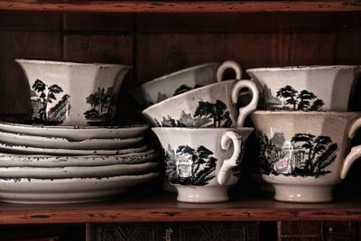 Close-up of old cups and saucers on cabinet