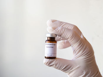 Close-up of hand holding bottle against white background