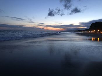 Scenic view of beach against sky at sunset