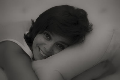 Close-up portrait of young woman relaxing on bed at home