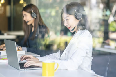 Young woman using mobile phone while sitting on table