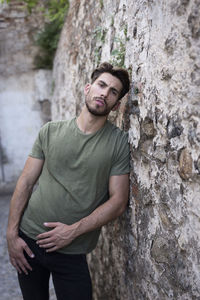 Muscular man leaning against a stone wall