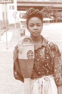 Portrait of woman standing by parking meter on land