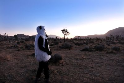 Side view of woman standing on landscape against sky