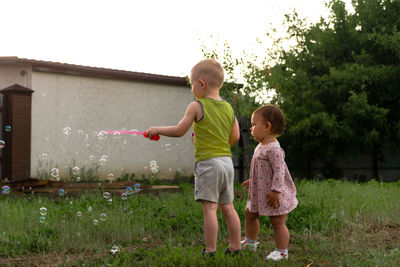 Siblings standing against plants