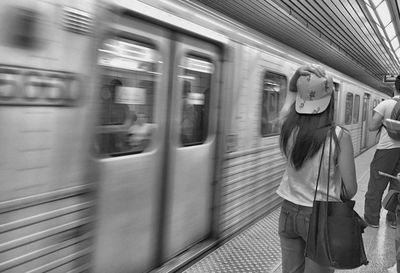 Rear view of woman standing on platform by metro train