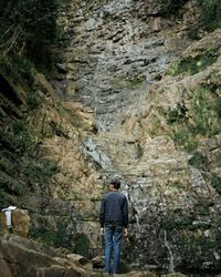 Rear view of teenage boy standing in front of rocky mountain