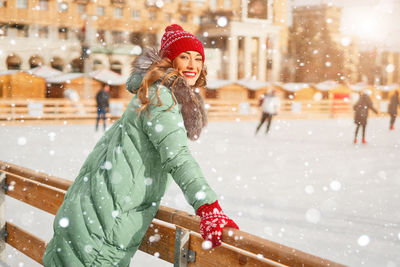 Portrait of smiling young woman wearing knit hat standing outdoors