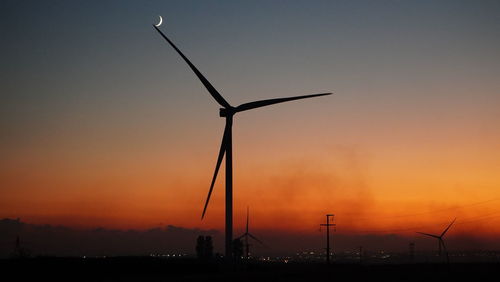 Silhouette windmills against sky during sunset