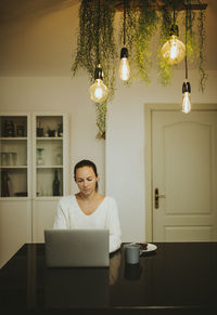 Full length of woman sitting on table at home