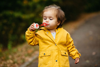 Cute boy holding yellow while standing outdoors