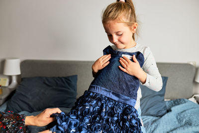 Mother and her daughter opening box with ordered dress at home on couch