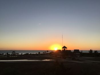 Scenic view of beach against clear sky during sunset