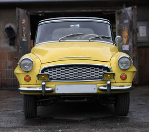 Close-up of yellow car parked on street in city