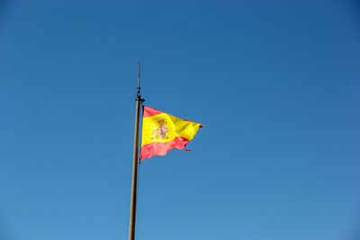 Low angle view of flag waving against blue sky