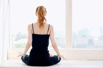 Rear view of woman sitting in window