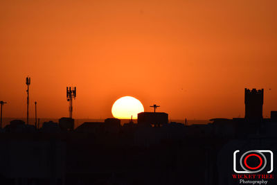 Silhouette buildings against clear sky during sunrise