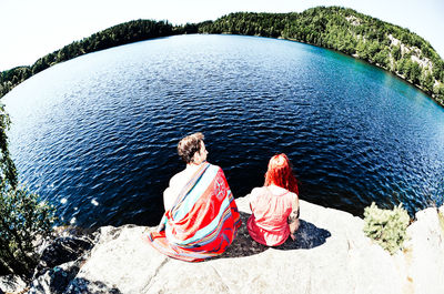 Rear view of young couple sitting on rock