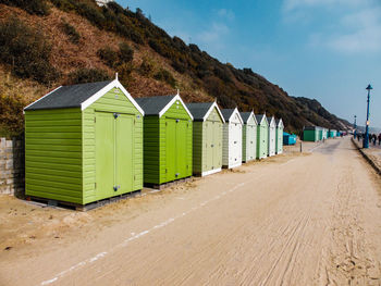 Beach huts by buildings against sky