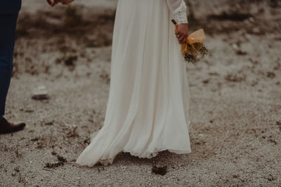 Midsection of woman with umbrella standing on field